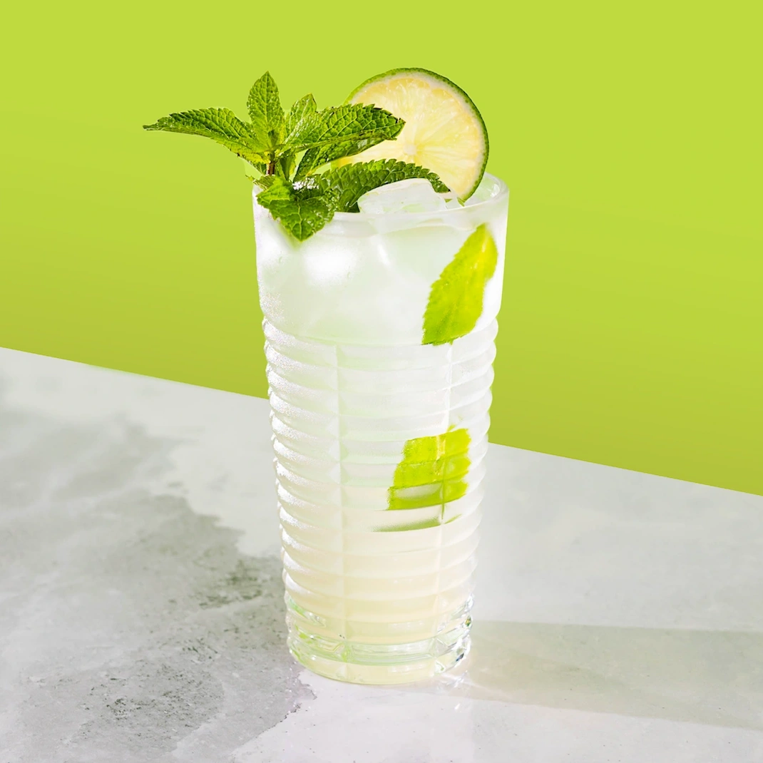 Cocktail à base de rhum, de mix à mojito et d'eau pétillante sur fond vert.