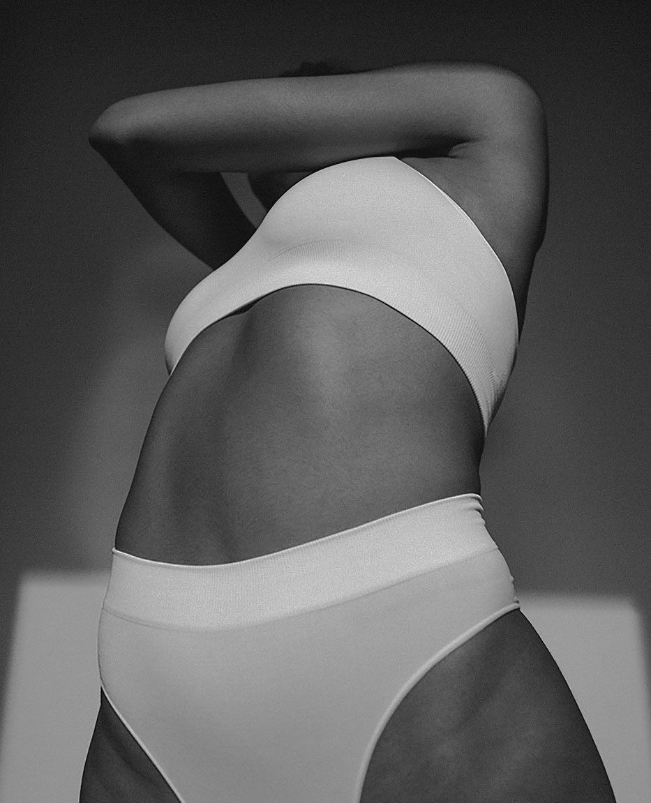 Black and white photo of woman in swimsuit stretching.