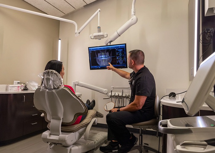 Dental professional reviewing a panoramic dental X-ray with a patient