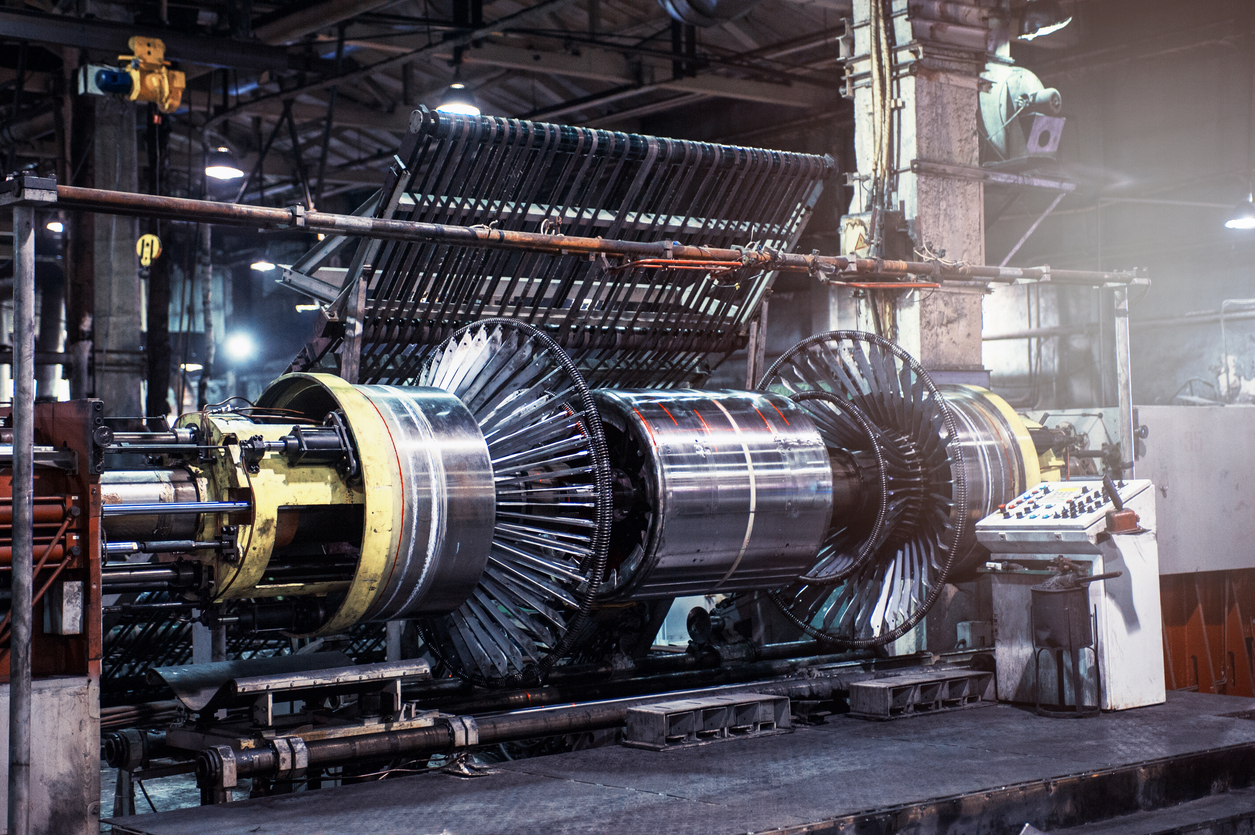 Large industrial machine with metallic cylindrical components and control panel in a factory setting.