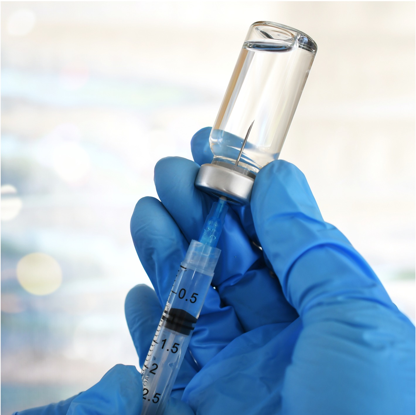 Gloved hands interacting with a vaccine vial
