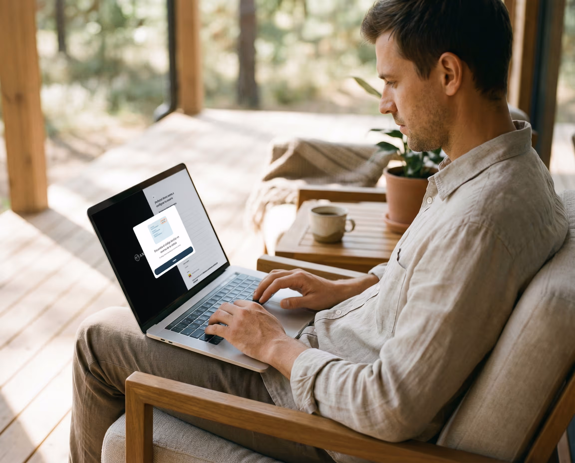 Hombre sentado frente a su casa usando una computadora portátil mientras registra su cuenta mediante validación de identidad por huella dactilar.