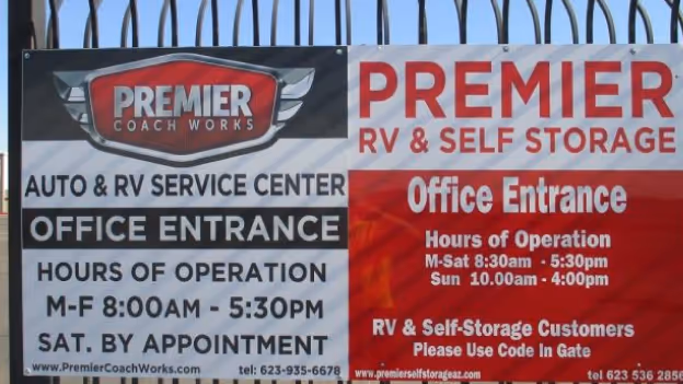 Metal sign for Premier Coach Works and Premier RV & Self Storage with office entrance hours and contact information.
