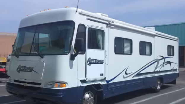 White and blue Allegro motorhome with windows and side door parked in a parking lot.