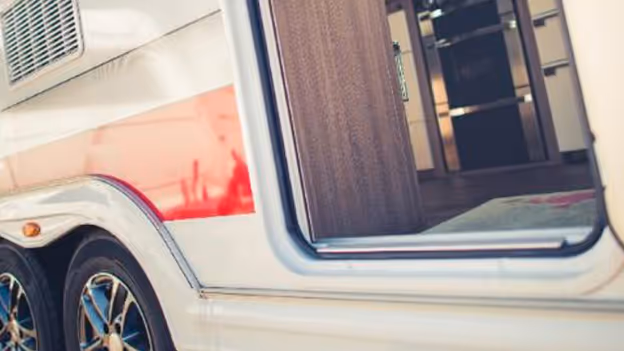 Close-up of an open door on a white RV showing black and chrome wheels and part of the interior floor.
