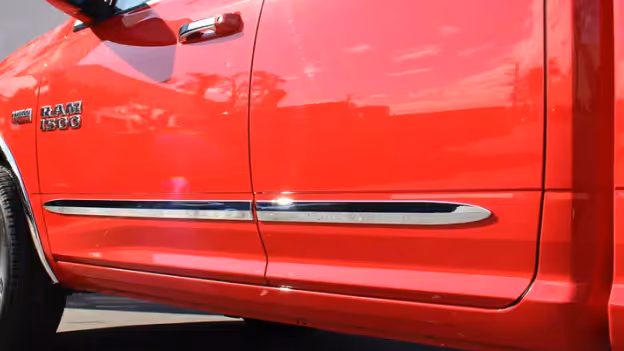 Chrome side molding installed on the lower door panel of a red Ram 1500 truck.