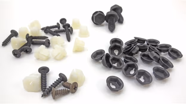 Various black screws and white plastic fasteners on a white background.