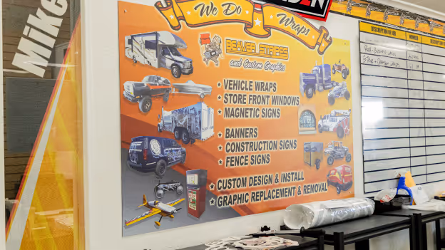 Interior wall sign listing vehicle wraps, storefront windows, magnetic signs, banners, construction signs, fence signs, custom design and install, and graphic replacement and removal services.