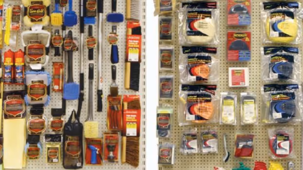 Store display of various car detailing brushes, sponges, and cleaning supplies hanging on pegboards.