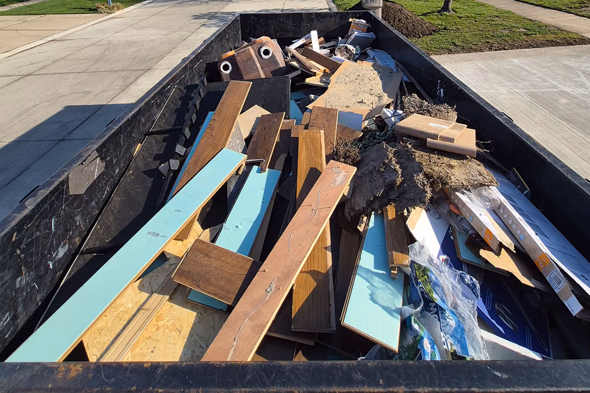 A dumpster filled with old wood and debris after a residential demolition service.