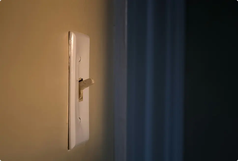 Close-up of a light switch mounted on a wall in low lighting