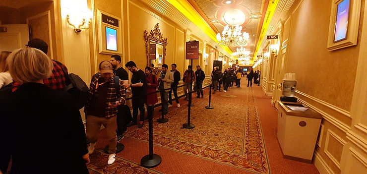 A long line of attendees waiting in a luxurious, gold-toned hallway for a speaking session on digital audio and modernization at AWS re:Invent.