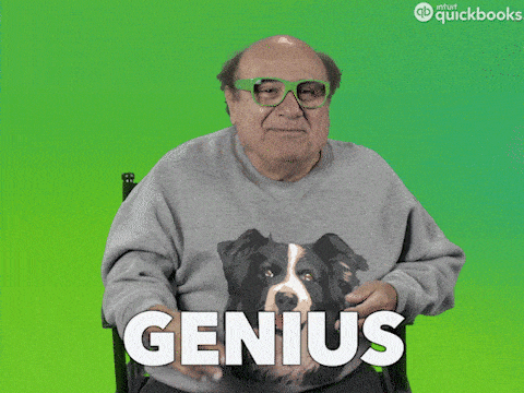 Danny DeVito wearing green glasses and a sweater with a dog on it, with the text "GENIUS" displayed below.
