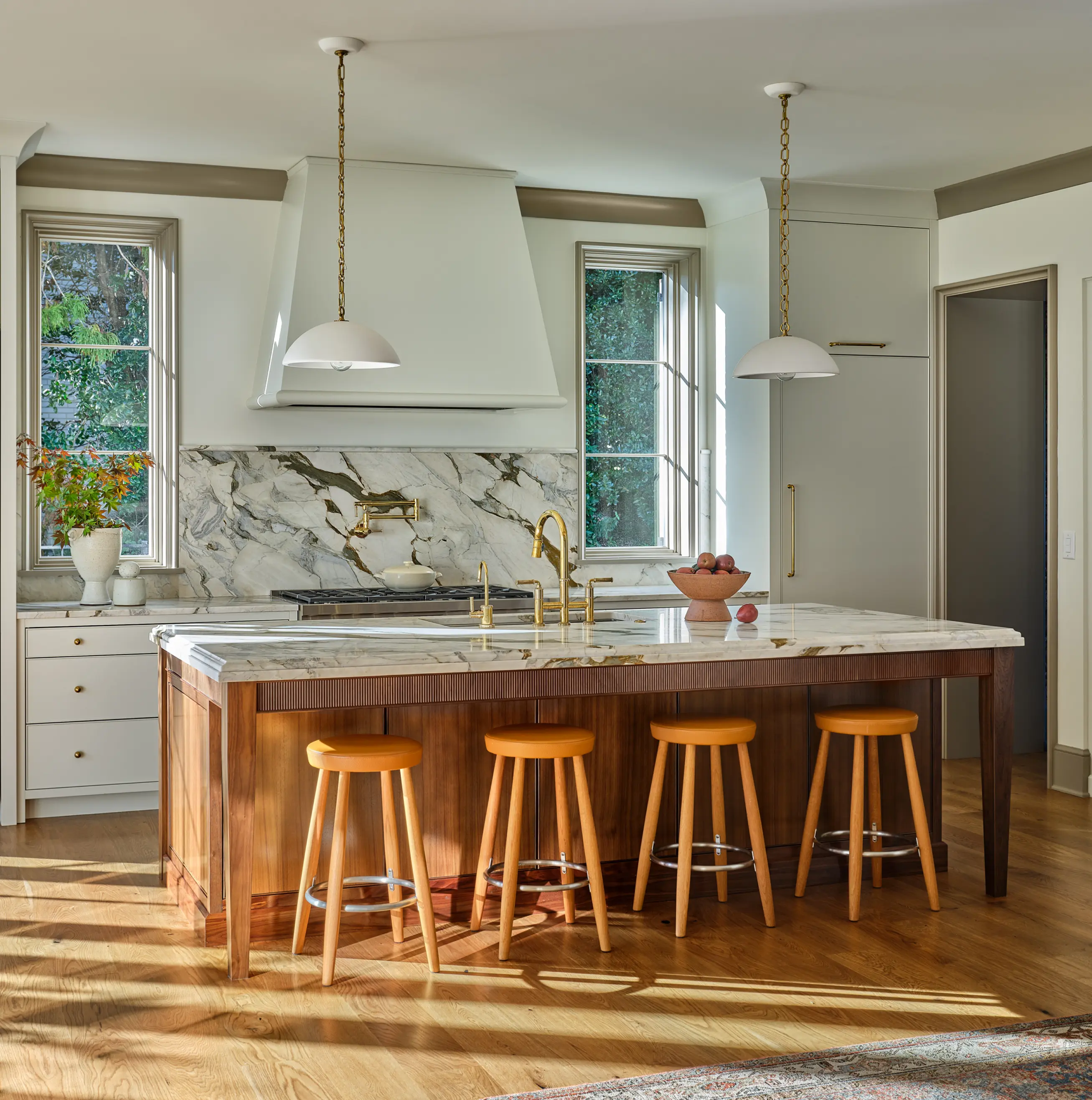 A renovated kitchen with island and chairs. Hanging lights and new appliances