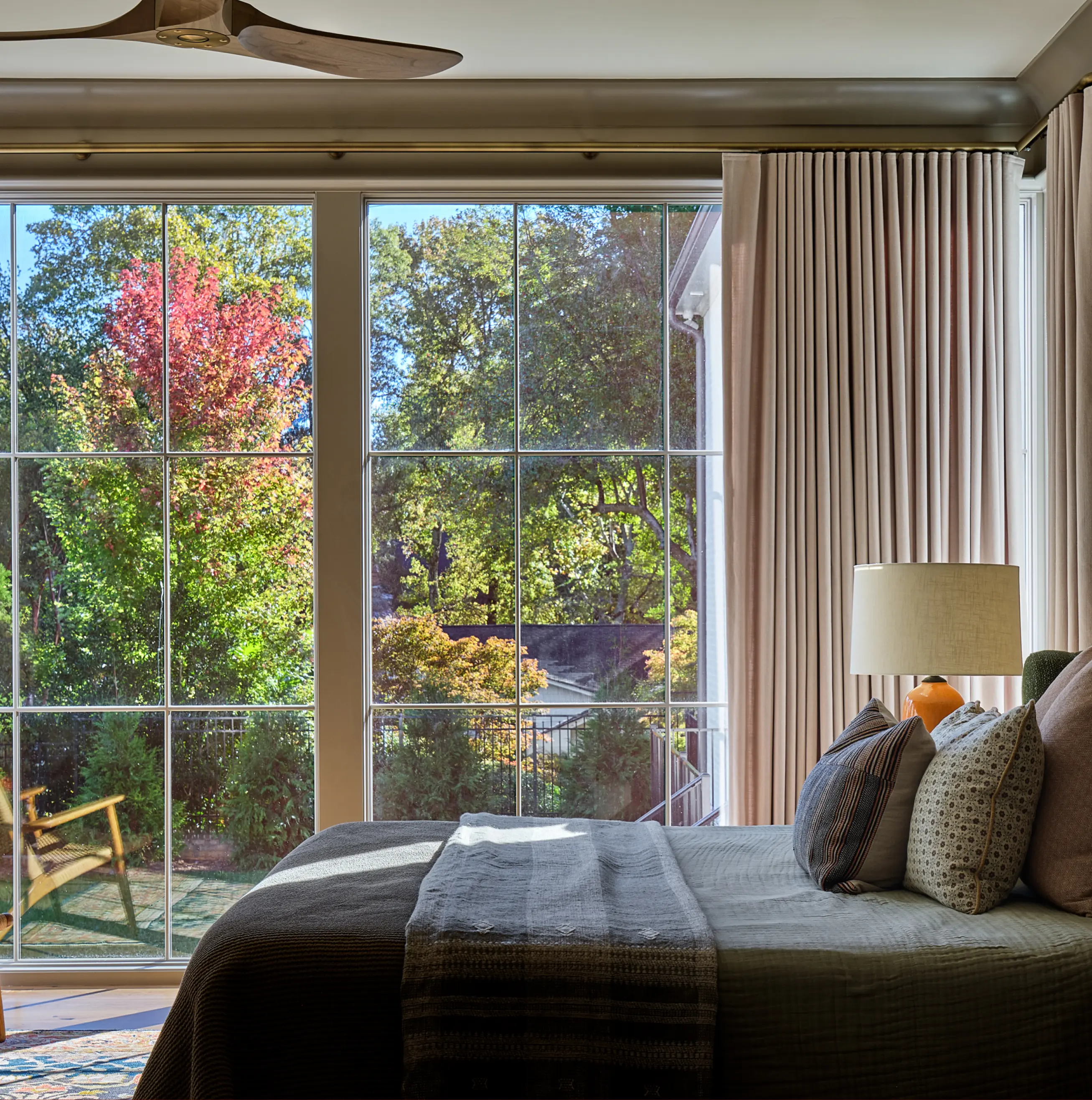 A bedroom with a large windows and curtains