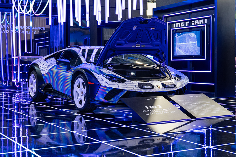 A professional trade show exhibit for Skechers Outdoor, featuring a large, high-resolution backlit graphic of a hiker on a mountain trail, clean white modular walls, and a suspended 'Skechers Trail' illuminated light box.