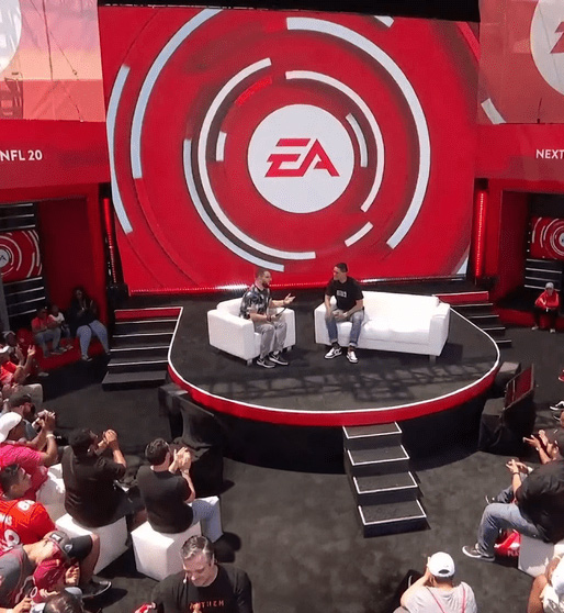 A vibrant, large-scale exhibition entrance for 'SK Wonderland' at CES, featuring a glowing teal marquee with carnival-style lighting and a massive digital globe displaying messages about a sustainable net-zero future, surrounded by a captivated audience.