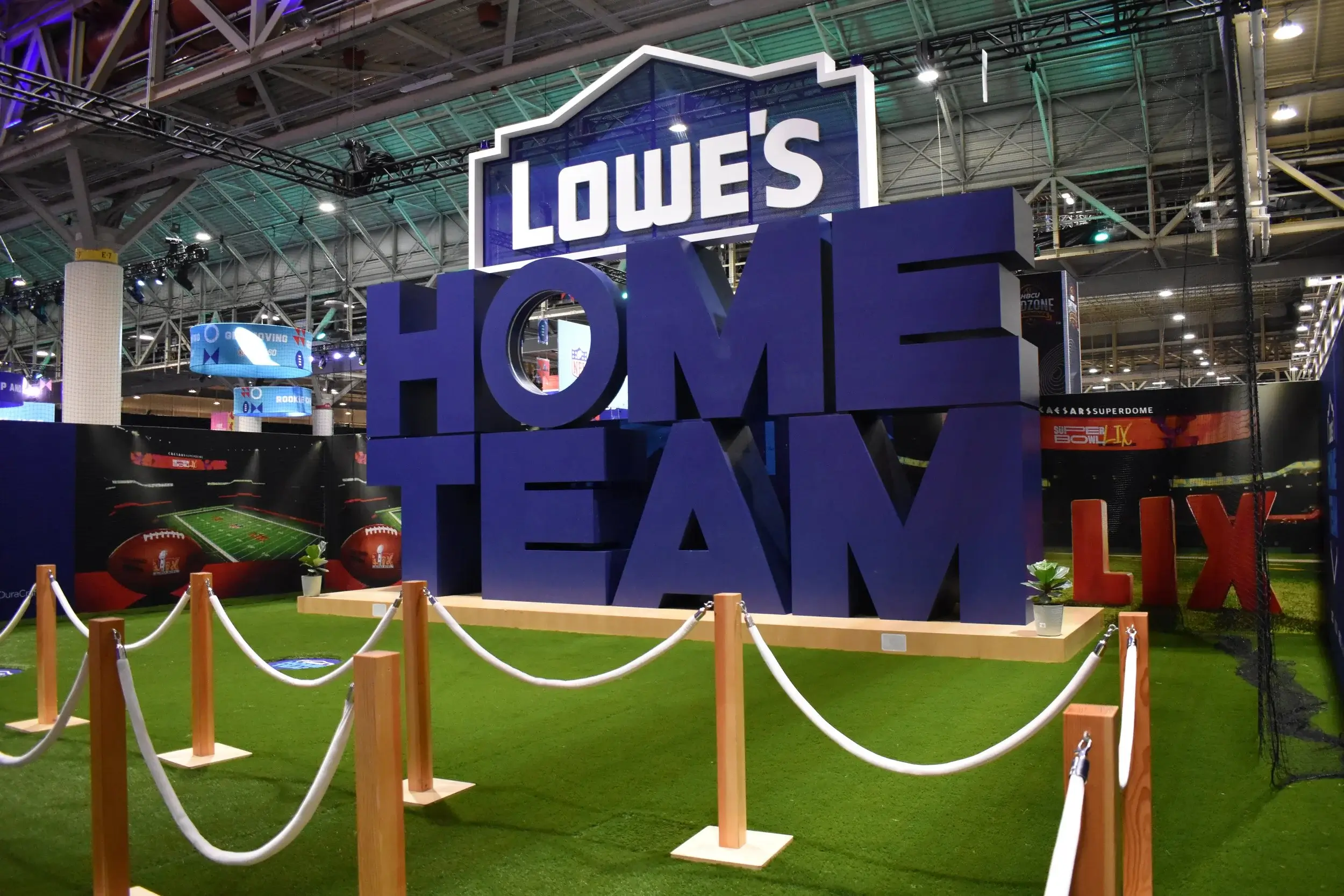 Large-scale environmental branding for Lowe's Home Team, showcasing custom-fabricated oversized lettering and branded stadium-themed backdrops within a professional convention hall setting.