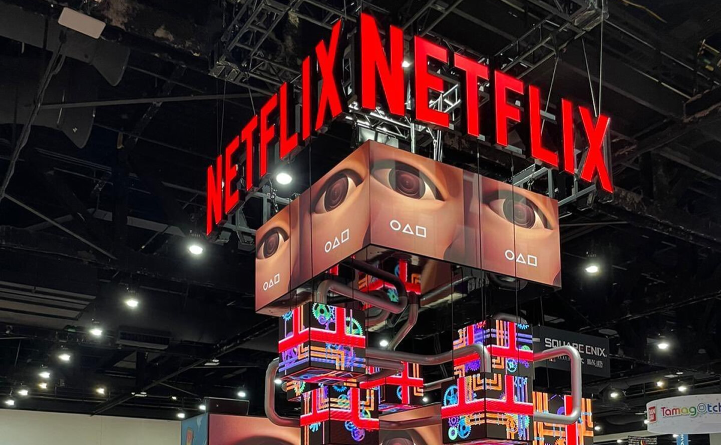 Suspended 3D digital display for Netflix featuring multi-faceted LED screens, intricate industrial piping, and bold illuminated red signage, showcasing advanced experiential design and brand activation.