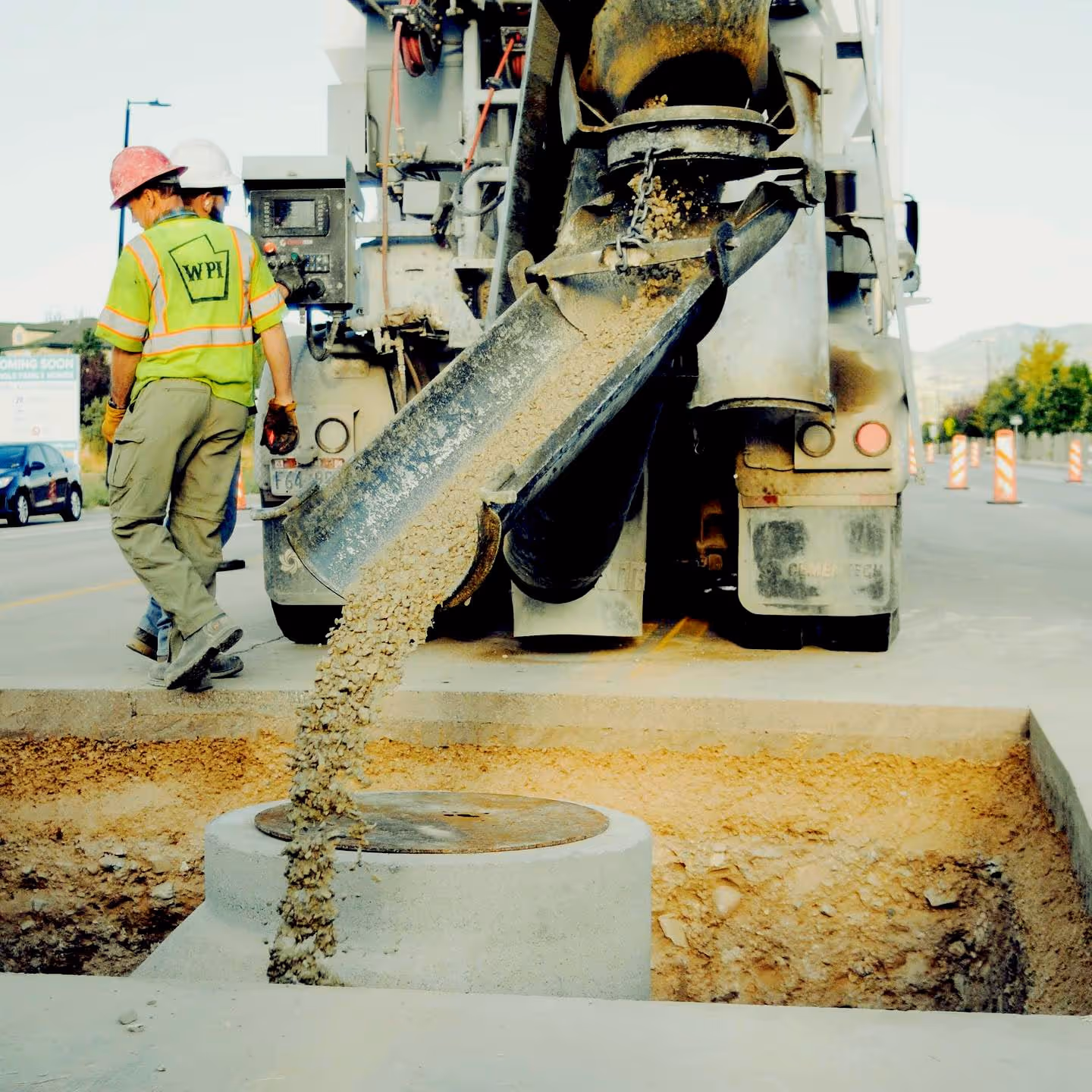 Volumetric concrete being poured around manhole.