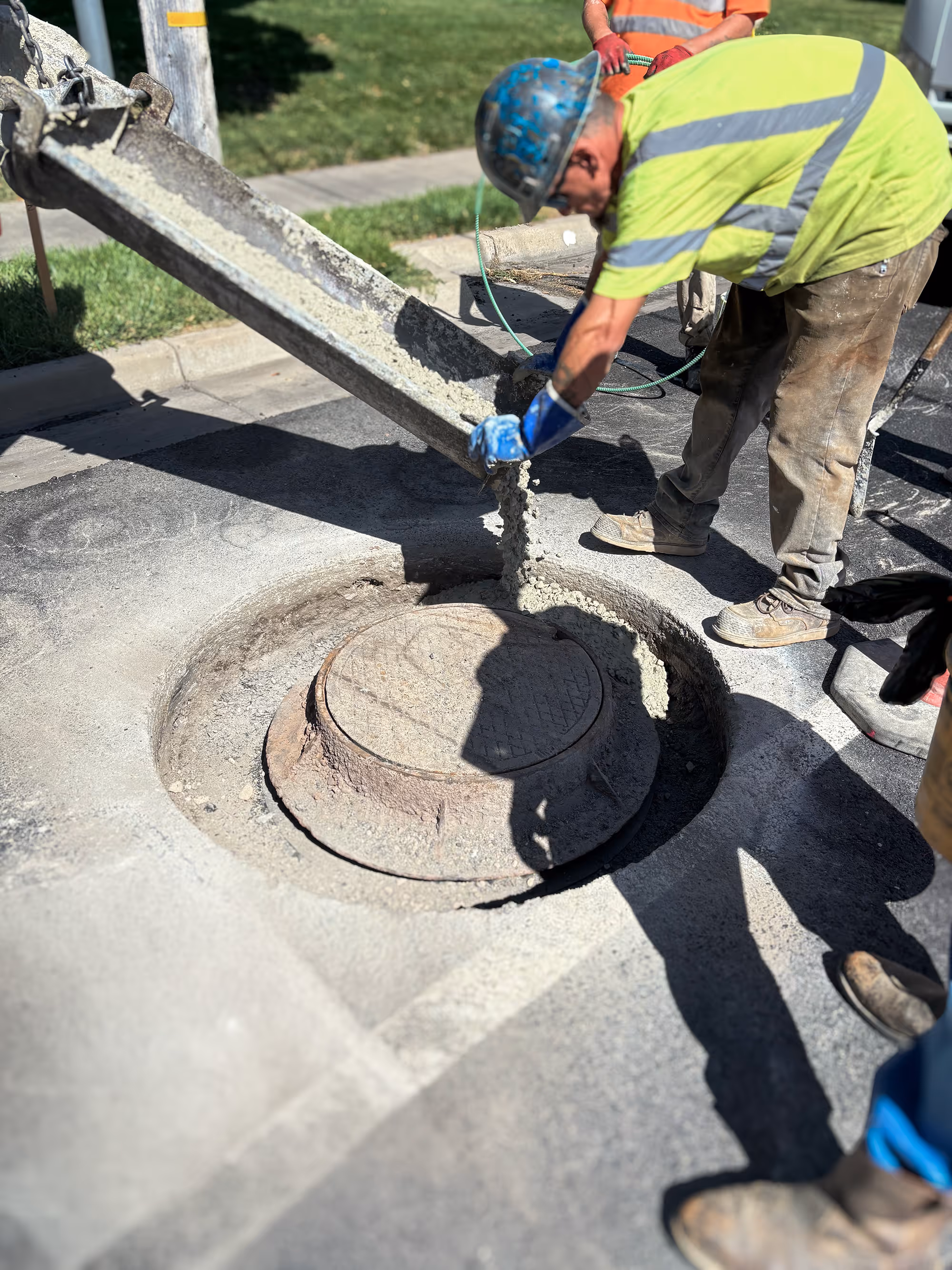 Man pouring concrete around manhole