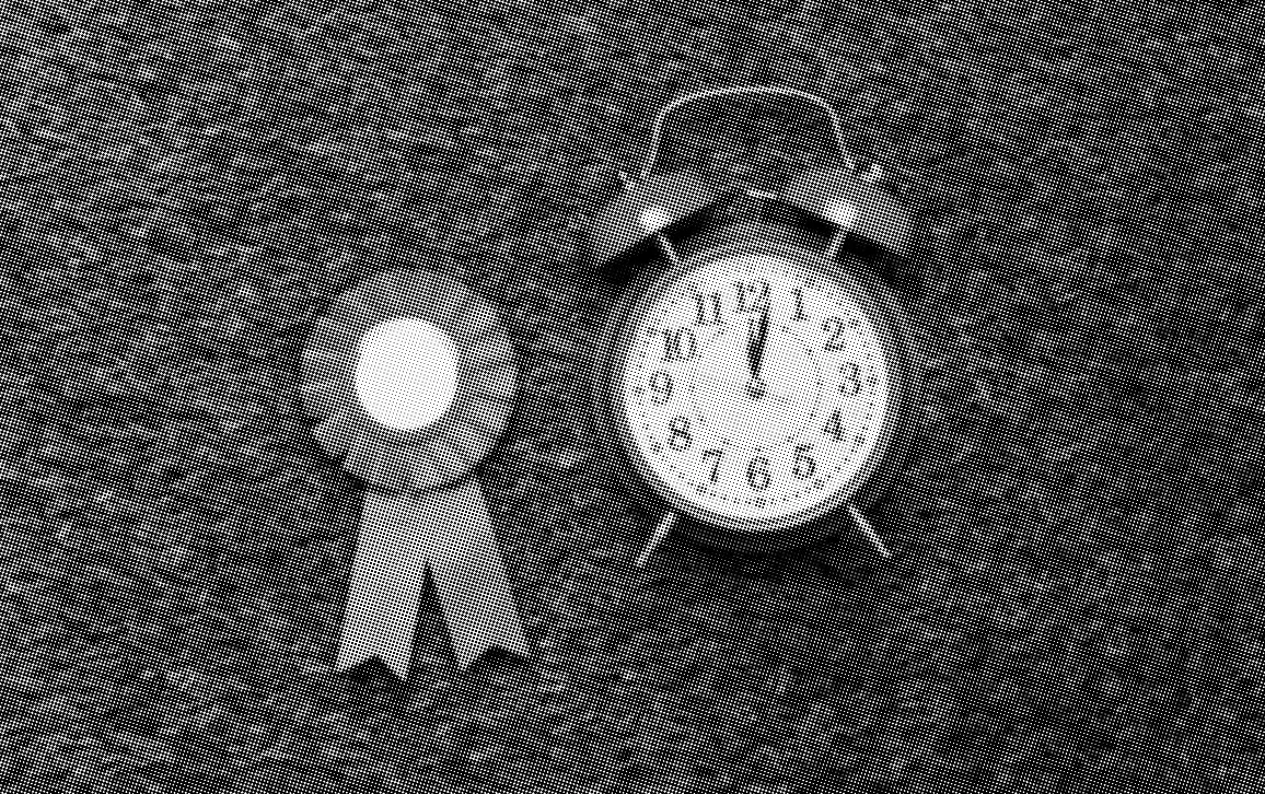 grayscale halftone image of an award ribbon and a round alarm clock on a fake grassy background