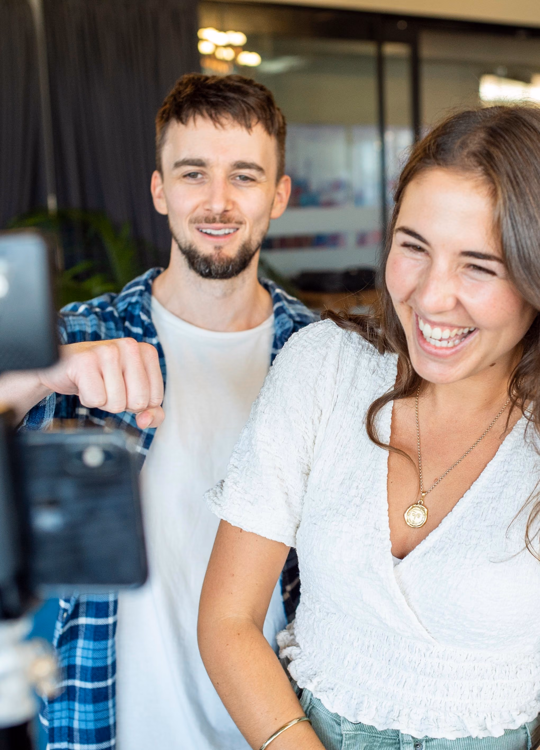 Smiling man and woman appear on a mobile phone screen, with man making a fist gesture.