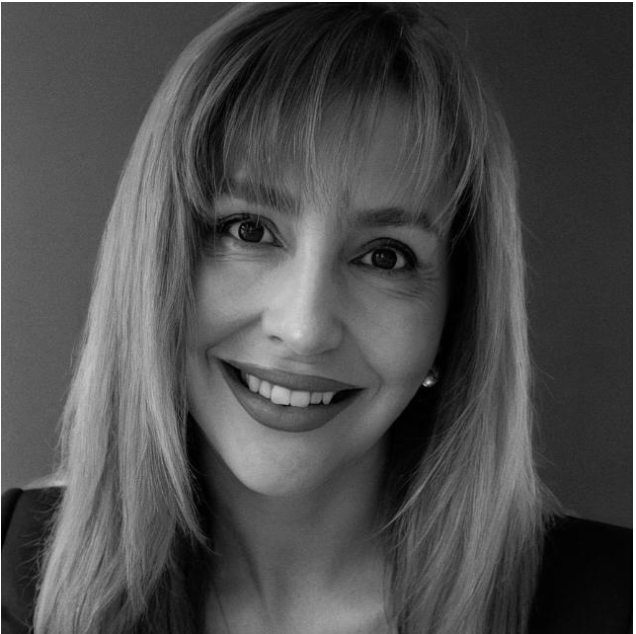 Black and white close-up portrait of a smiling woman with straight hair and bangs.