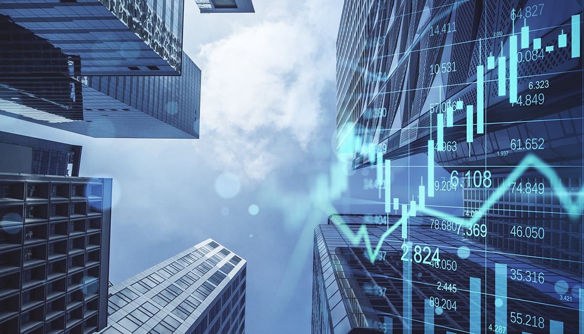 Upward view of modern skyscrapers with overlaid transparent financial charts and data graphs.
