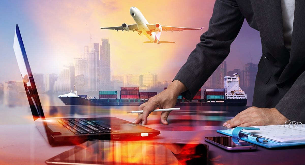 Businessman working on a laptop with a tablet, smartphone, and planner nearby, with an overlay of a cargo ship, airplane, and city skyline at sunset.