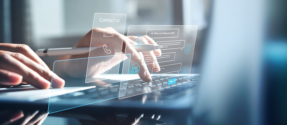 Person typing on a laptop keyboard with holographic chat and contact icons overlayed.