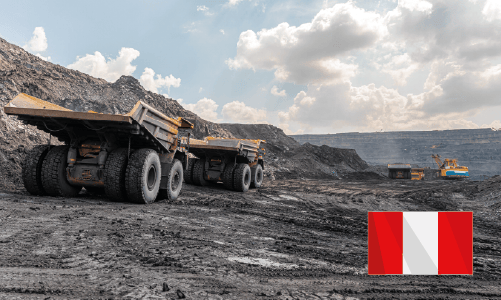 Large dump trucks and excavator working in an open-pit mining site under a cloudy sky.