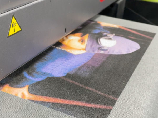 An image of a Direct to garment machine printing a photo of usher onto a shirt.