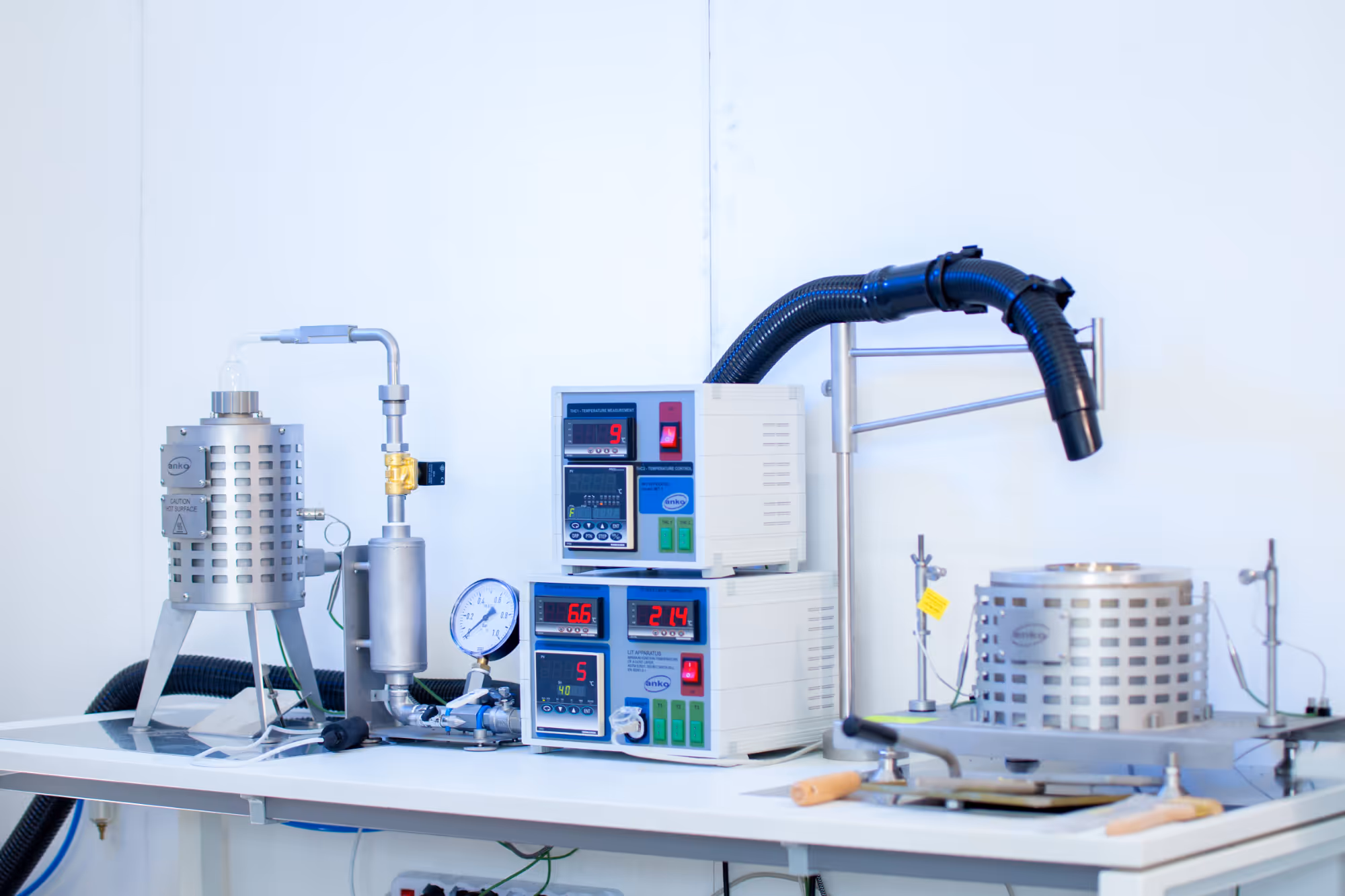 Laboratory setup with temperature control devices, gauges, and metal equipment on a white table.