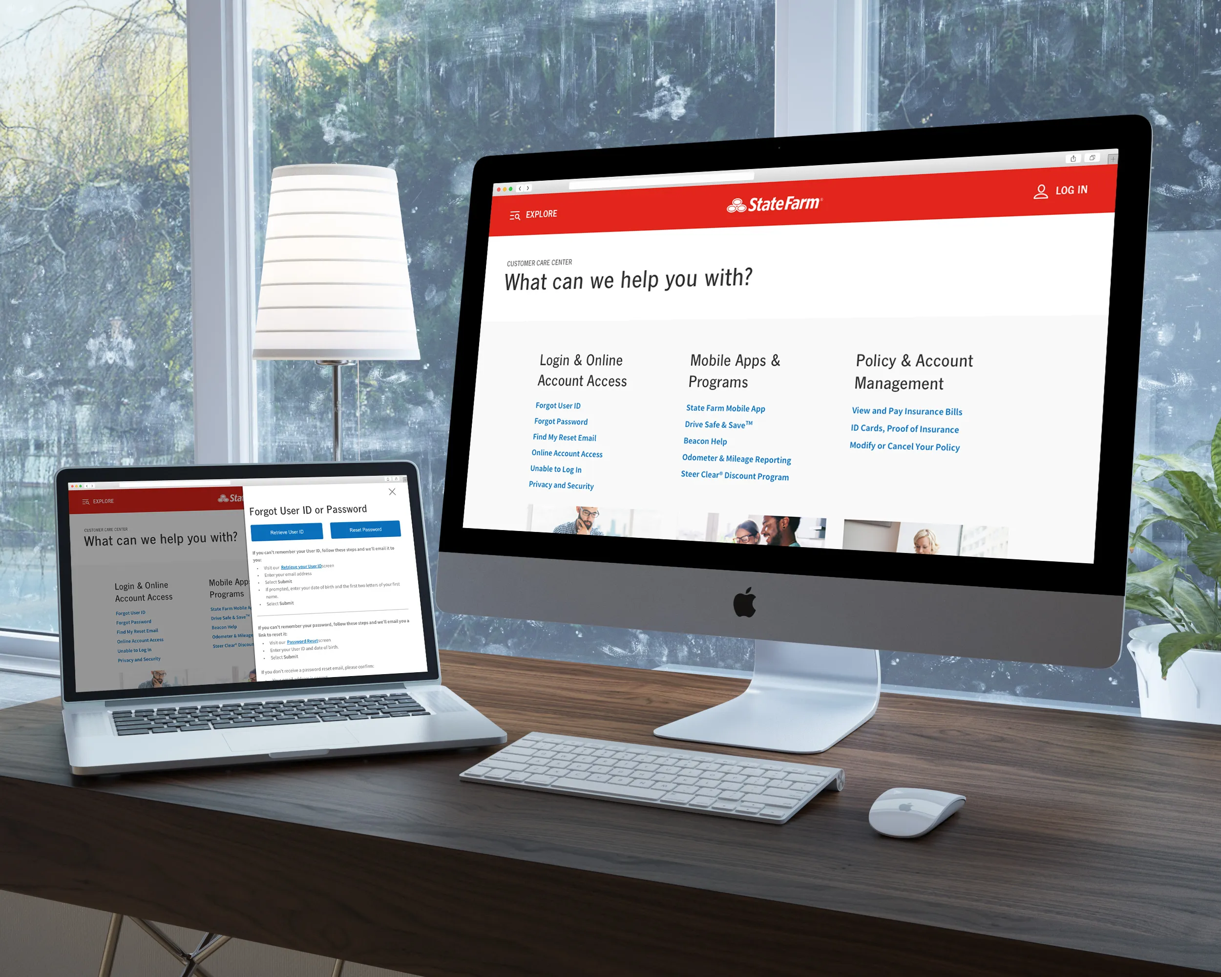 Modern workspace with an iMac and a laptop showing State Farm customer care website pages on a wooden desk by a window.