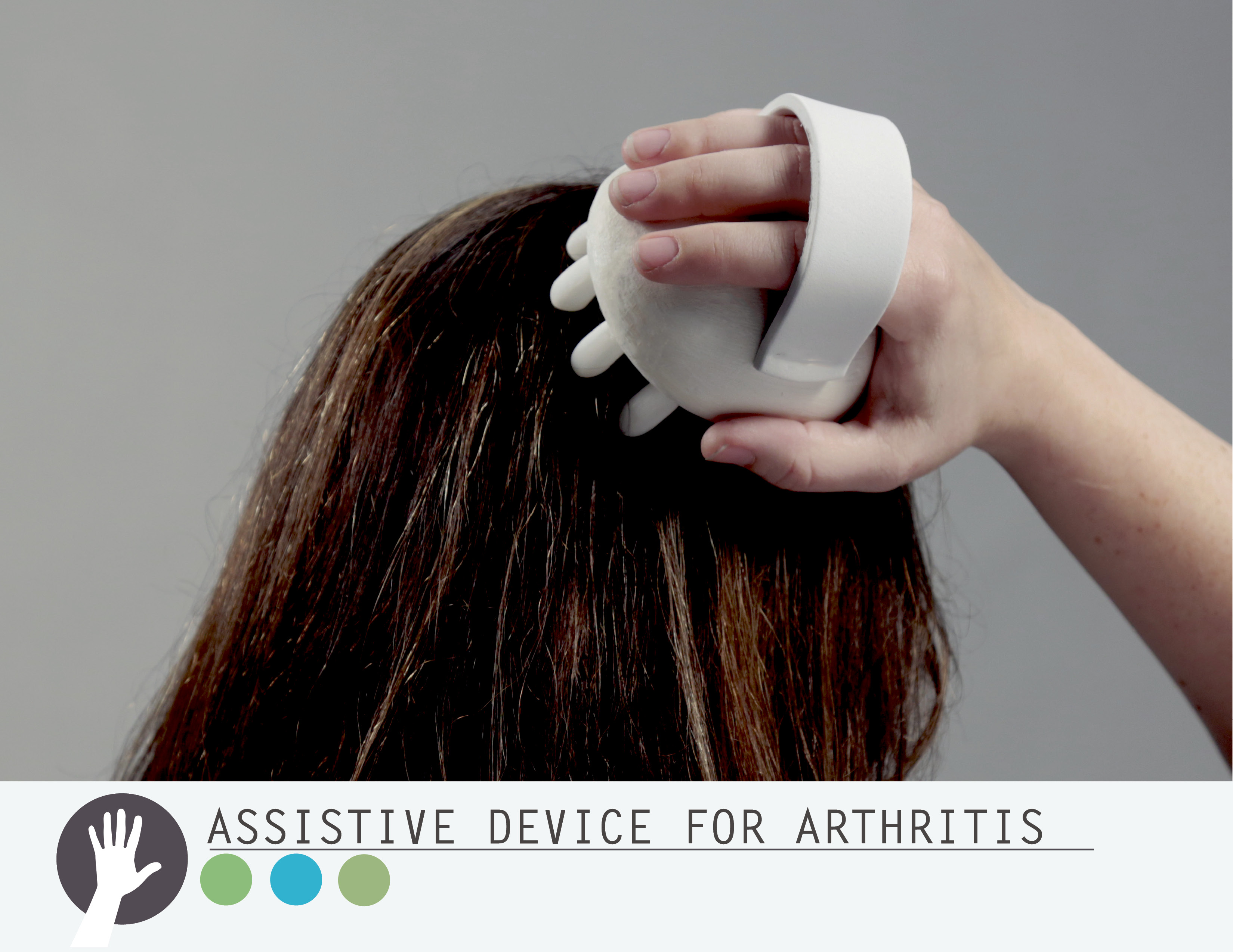 Hand using a white assistive device to massage scalp of dark brown hair against gray background.