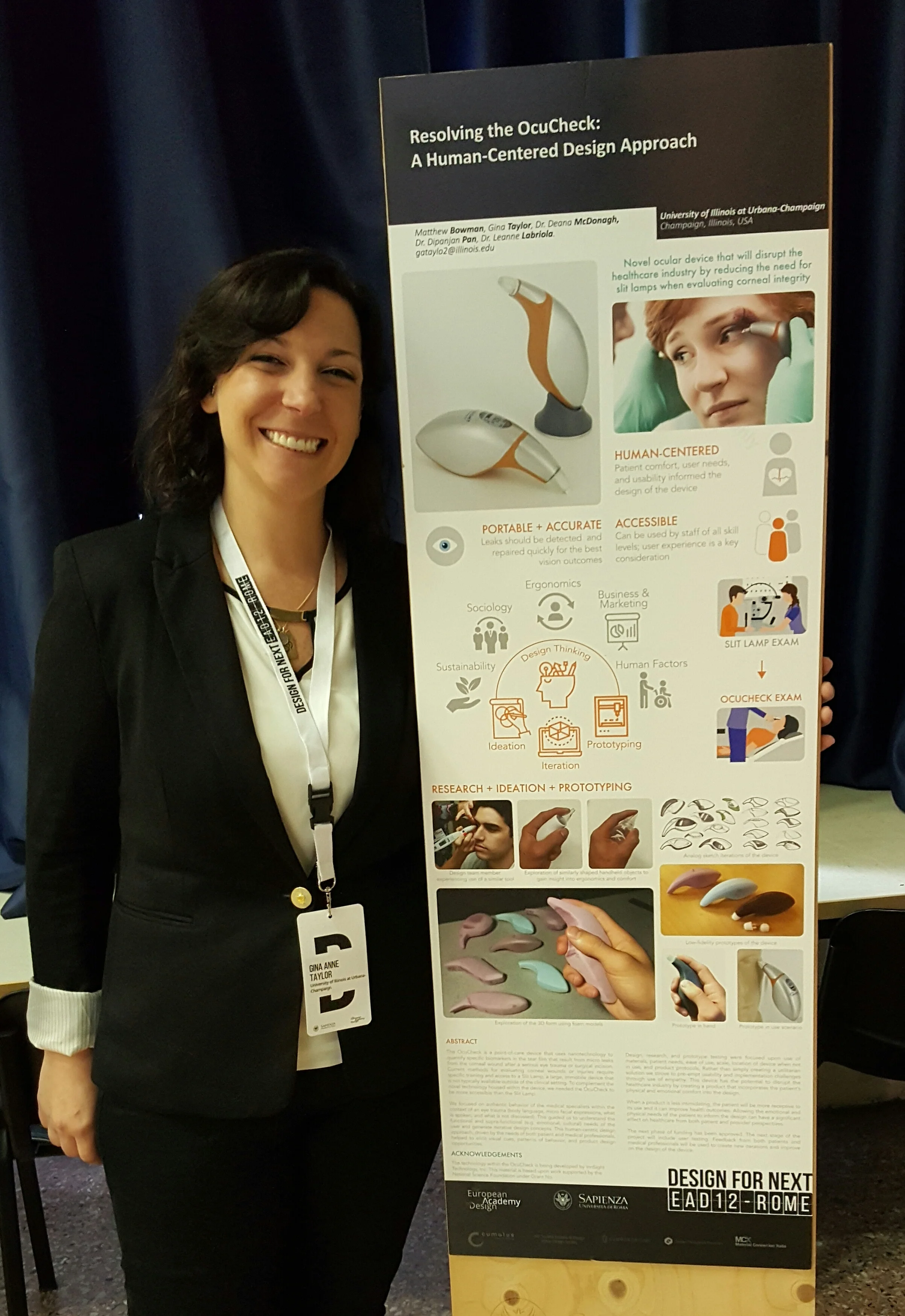 Smiling woman in black blazer standing next to a poster titled 'Resolving the OcuCheck: A Human-Centered Design Approach' about an ocular device at a design event.