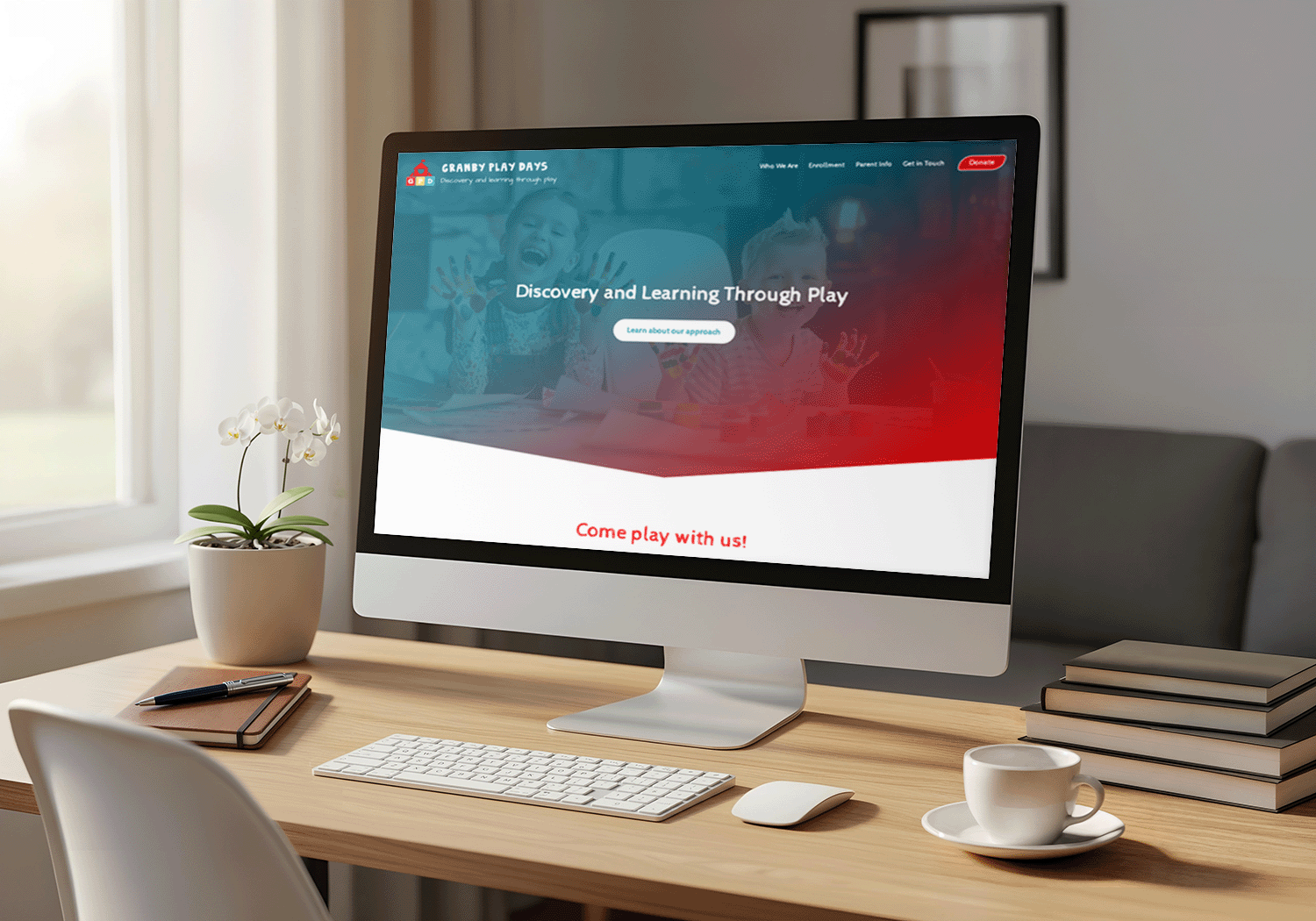 Desktop computer on a wooden desk displaying Granby Play Days website with children and the text 'Discovery and Learning Through Play.'