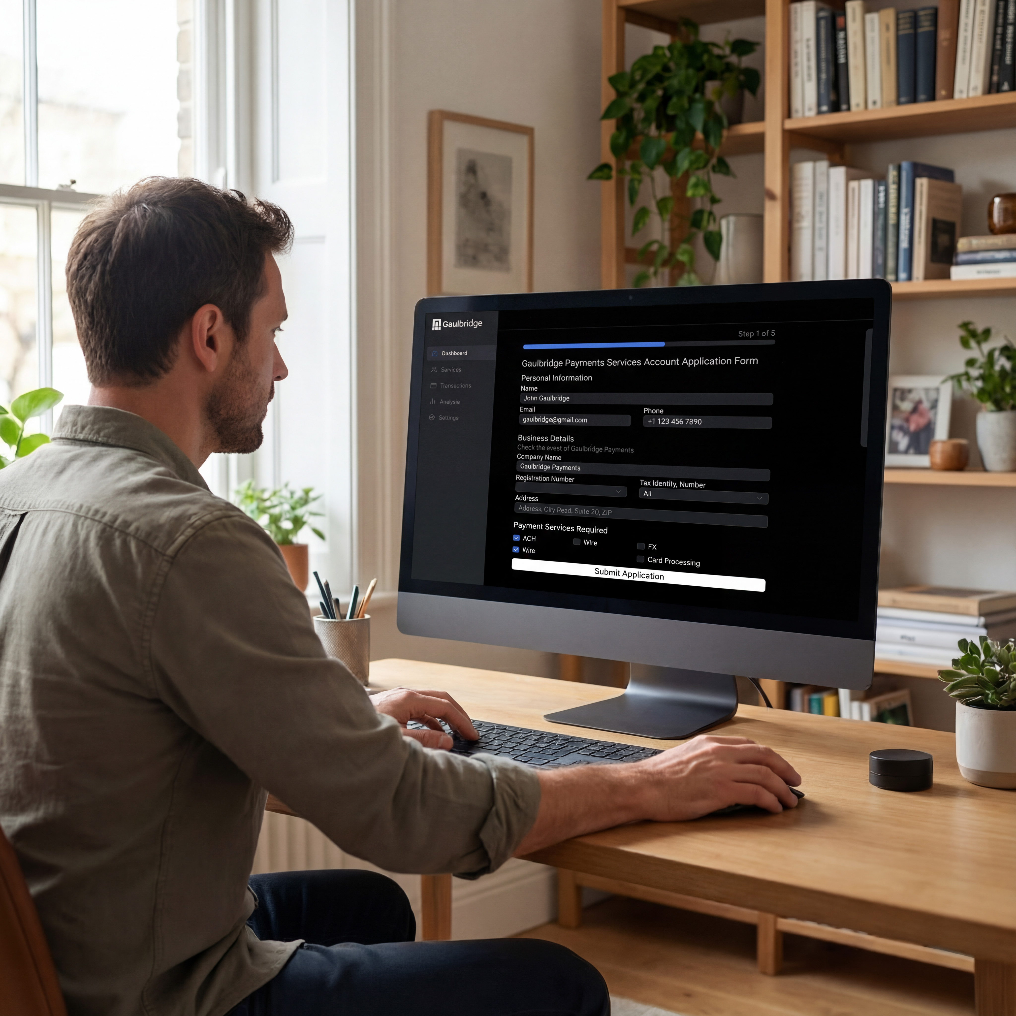 Man sitting at a wooden desk filling out Gaulbridge Payments Services account application on a computer screen in a bright home office.