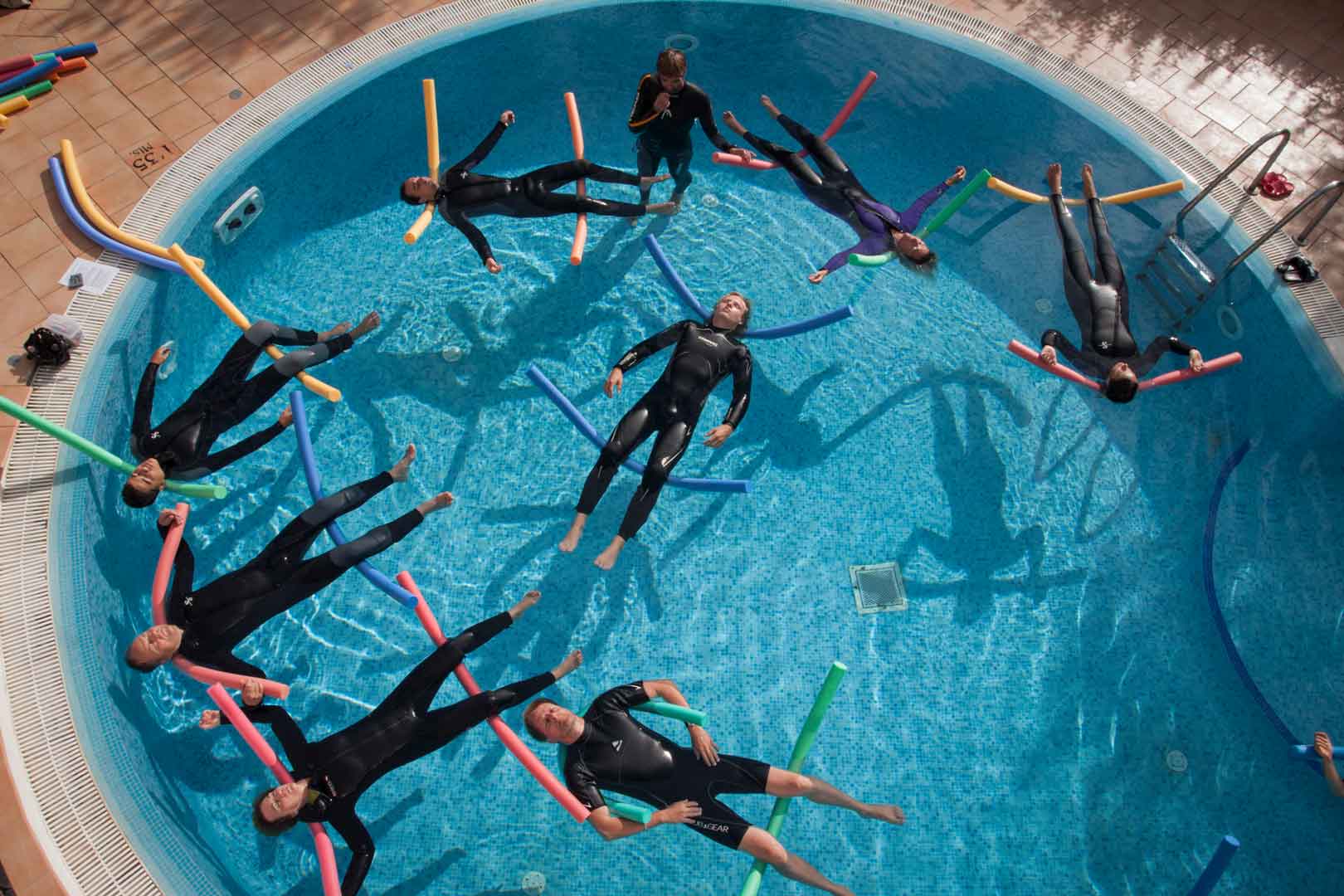 Eine Gruppe Relaqua-Kurs-Teilnehmende treibt im Pool und entspannt. Draufsicht von einer Drohne aufgenommen. Relaqua live!