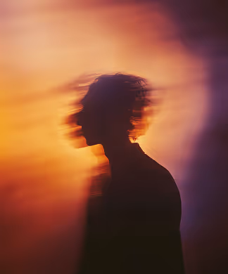 Silhouette of a person with blurred motion effect against a gradient background of warm orange and purple tones.