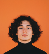 Young boy with outstretched arms outdoors with seagulls flying around him.