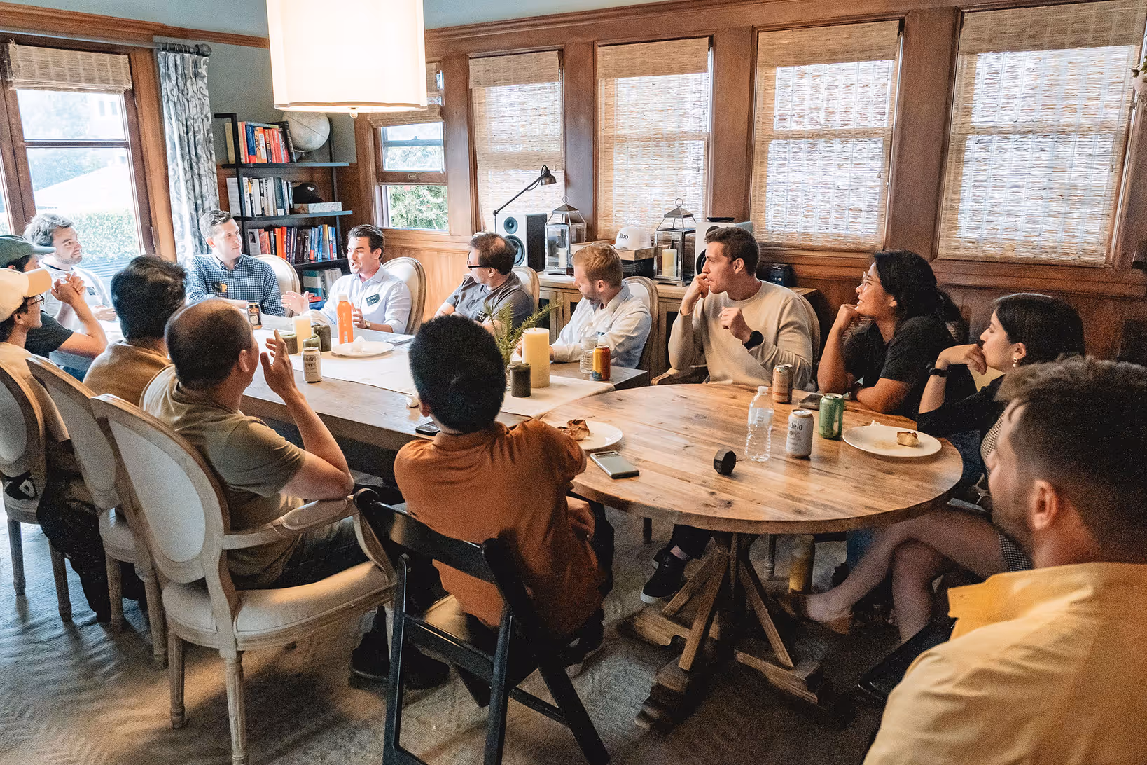 Group of friends gathered around a poker table playing a card game indoors at night.
