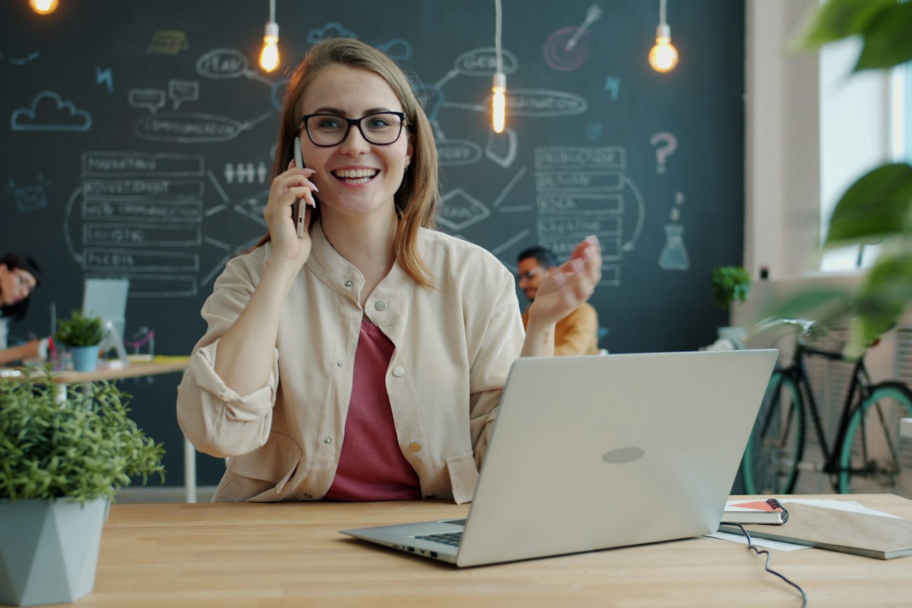 Office worker smiling while taking a phone call at her desk