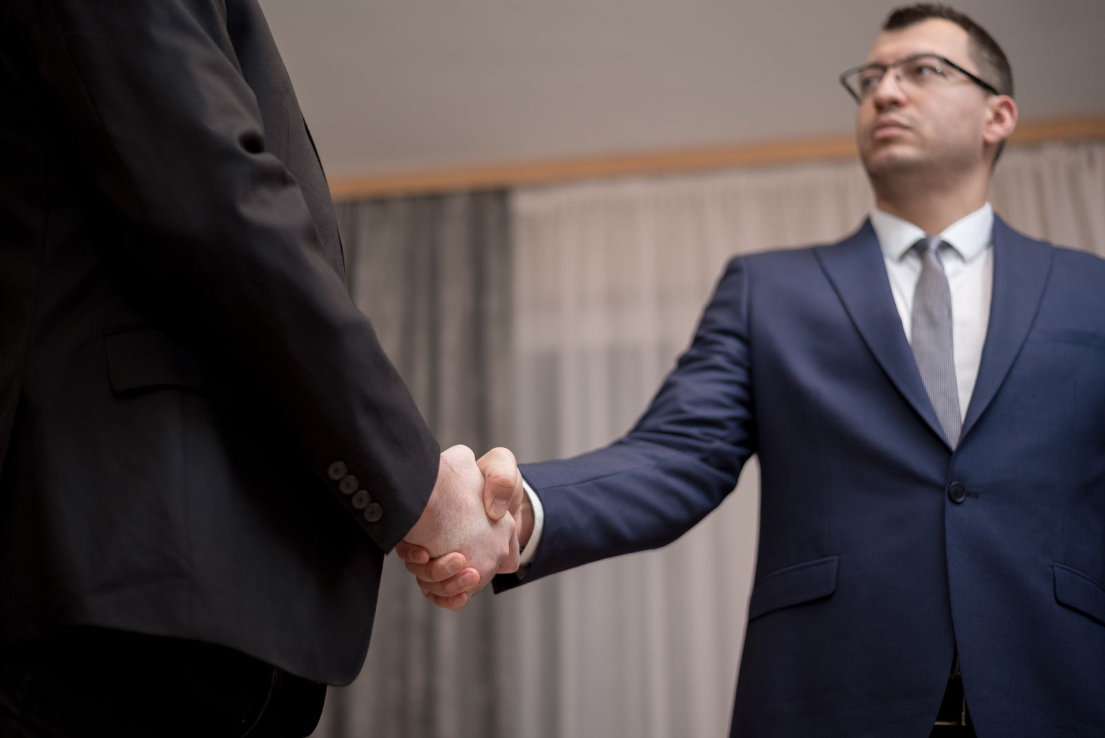 Deux hommes en costume se serrant la main dans un bureau