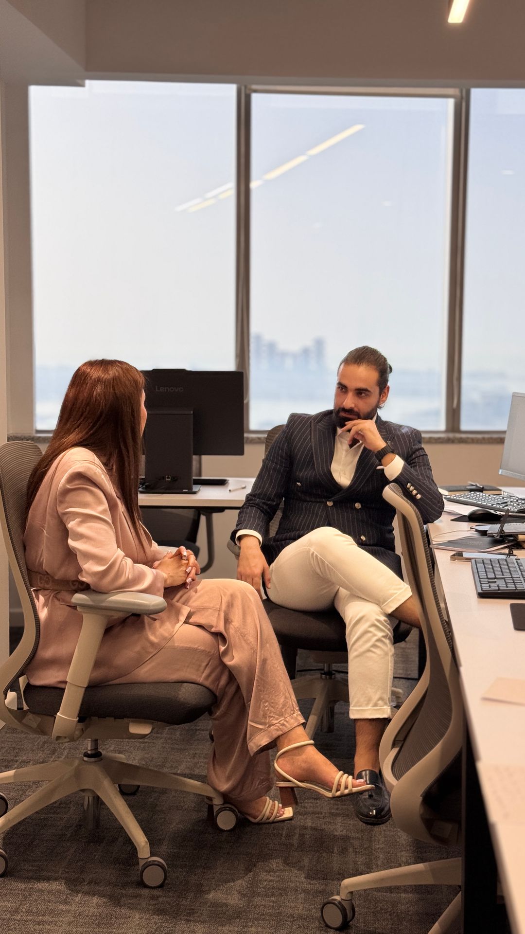 Deux professionnels assis face à face échangent dans un bureau moderne aux larges baies vitrées