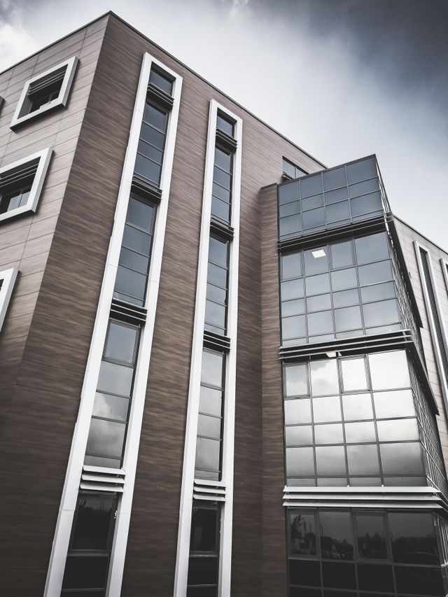 Façade d'un immeuble de bureaux moderne en briques sombres et verre, vue en contre-plongée