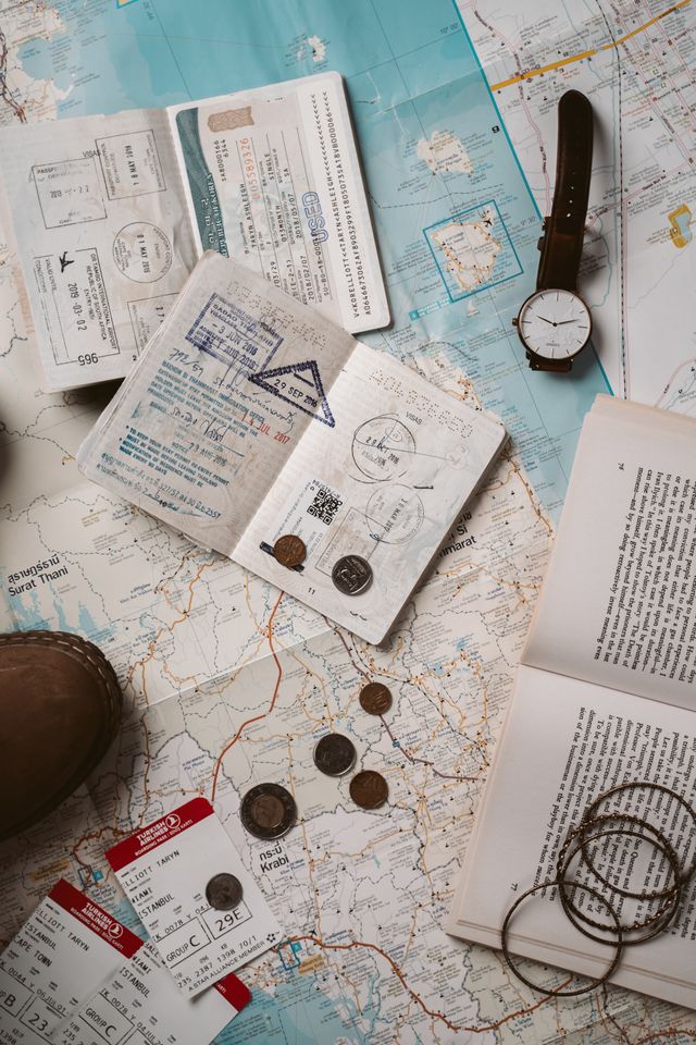 Passeports tamponnés, carte routière, montre, pièces et billets de transport étalés sur une table