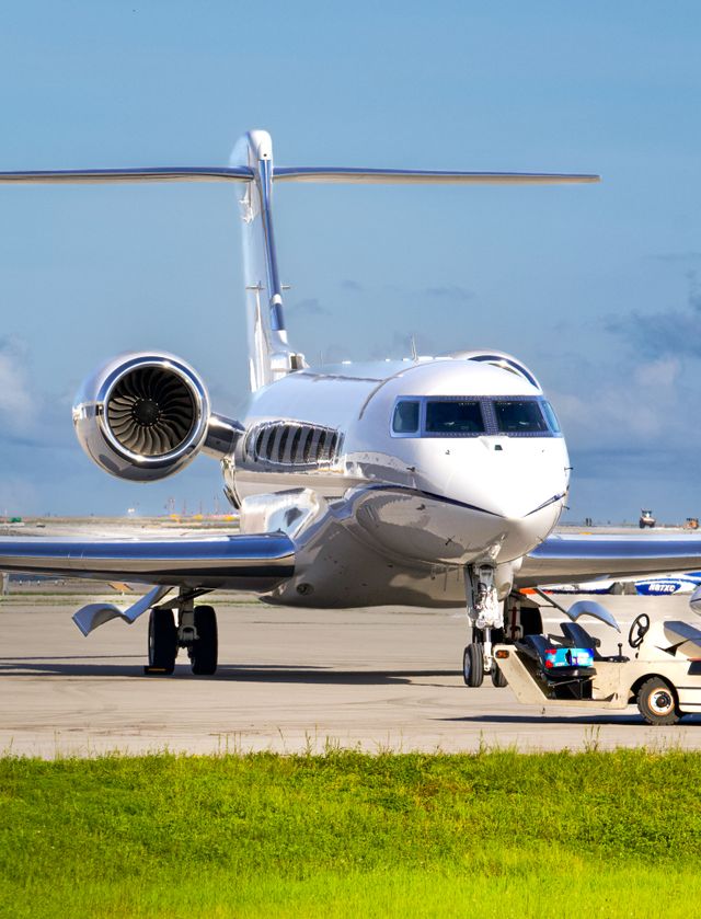 Jet d'affaires blanc stationné sur le tarmac d'un aéroport, vu de face sous un ciel bleu