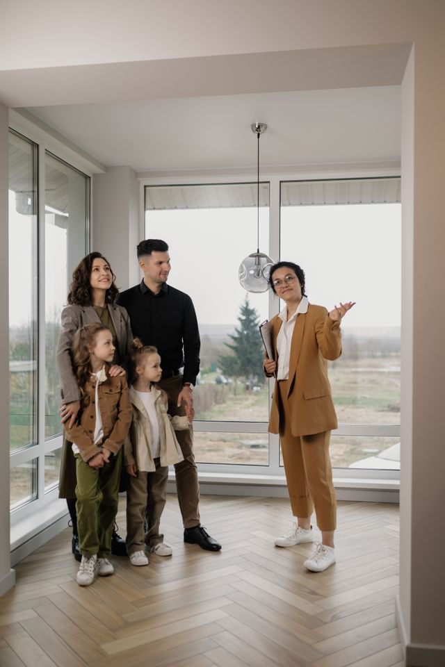 Famille avec deux enfants visitant un appartement vide et lumineux en compagnie d'une agente